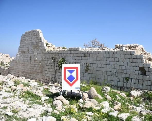 Ancient stone wall of Chamaa citadel with Blue Shield protection sign in the foreground